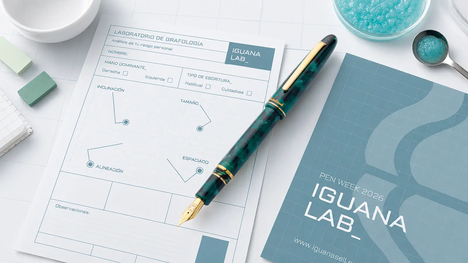 Fiche du Laboratoire de graphologie d’Iguana Lab avec un stylo plume Esterbrook vert et le dépliant Pen Week 2026