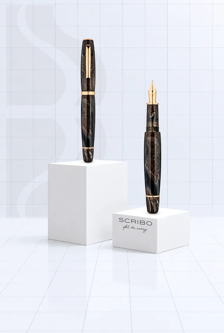 Deux stylos plume Scribo en résine brune marbrée avec détails en or rose, sur des socles blancs