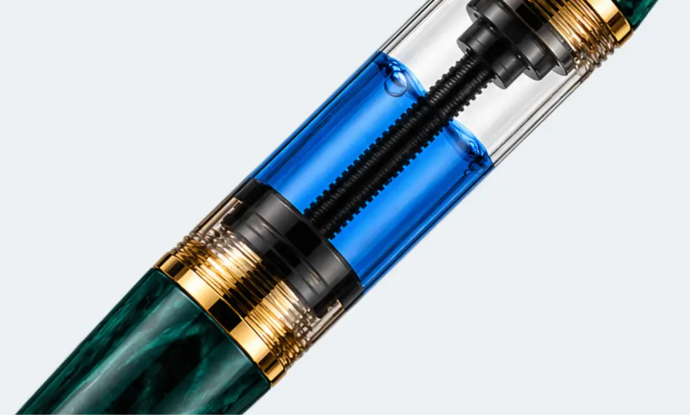 Système à piston plongeur rempli d’encre bleue dans un stylo plume en résine verte